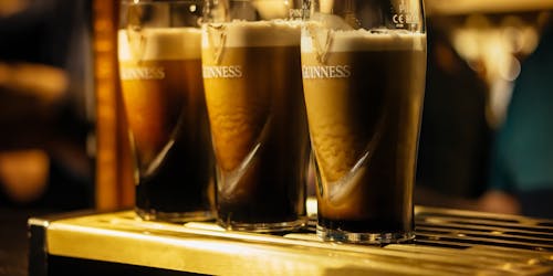 Three pints of Guinness, mid-pour, settle on a bar