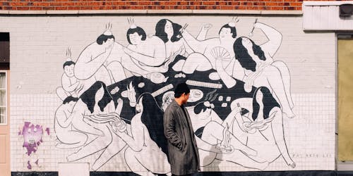 Man in black coat stood in front of mural