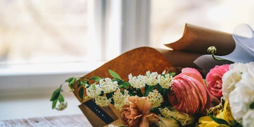 A bouquet of flowers lies beside a window