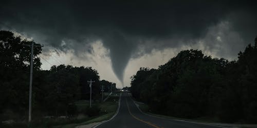 A tornado on the horizon at the end of a road