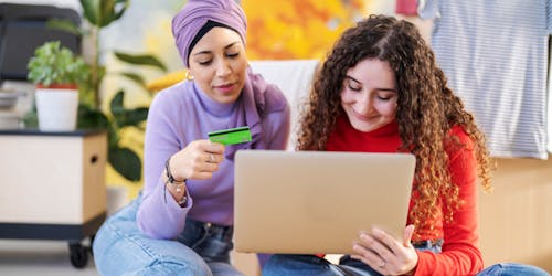 Two people sat together looking at a laptop