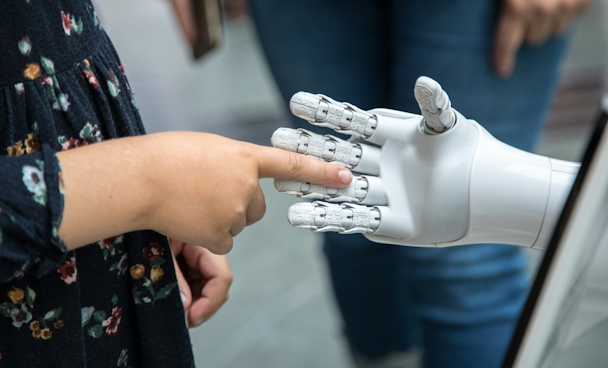 A human finger reaching into the open palm of a robot