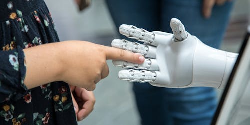 A human finger reaching into the open palm of a robot