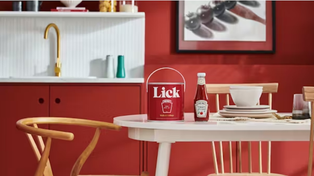 A pot of ketchup colored paint and a jar of ketchup on a table 