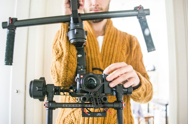 A man stands behind a camera rig