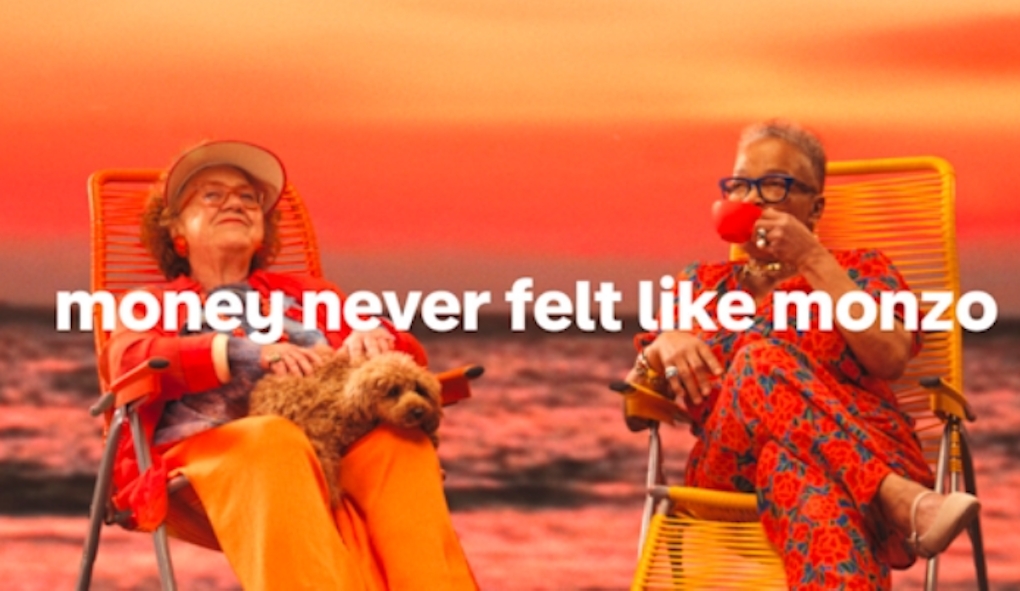 Two older women sitting on deck chairs on a beach 