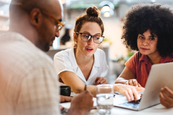 Three people sat around a laptop