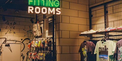 A fitting room in a clothes shop with a neon sign