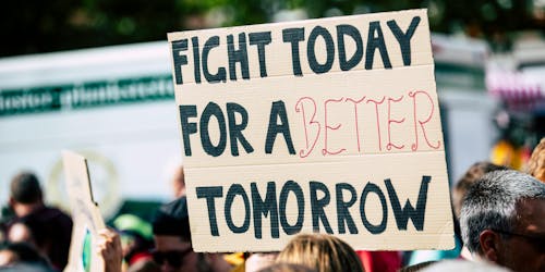 Person holding up a protest sign that says 'fight today for a better tomorrow'