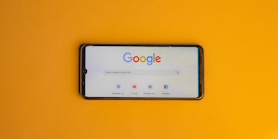 Image of a phone with Google search open on a yellow background 