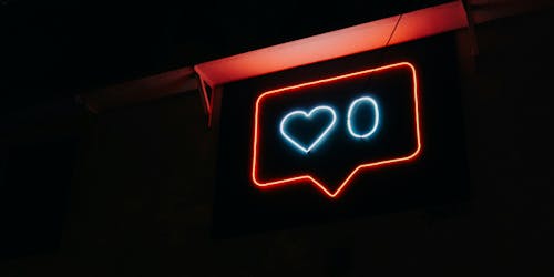 A neon sign shows a speech bubble in red with a 'zero likes' sign inside in blue