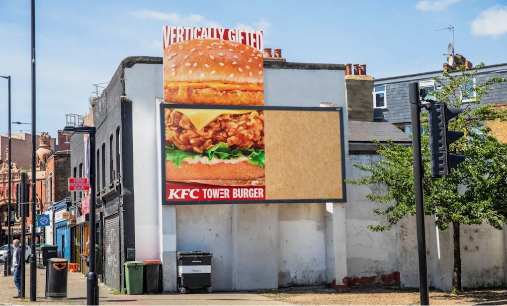 The KFC vertical billboard with the artwork coming over the top of the frame of the hoarding