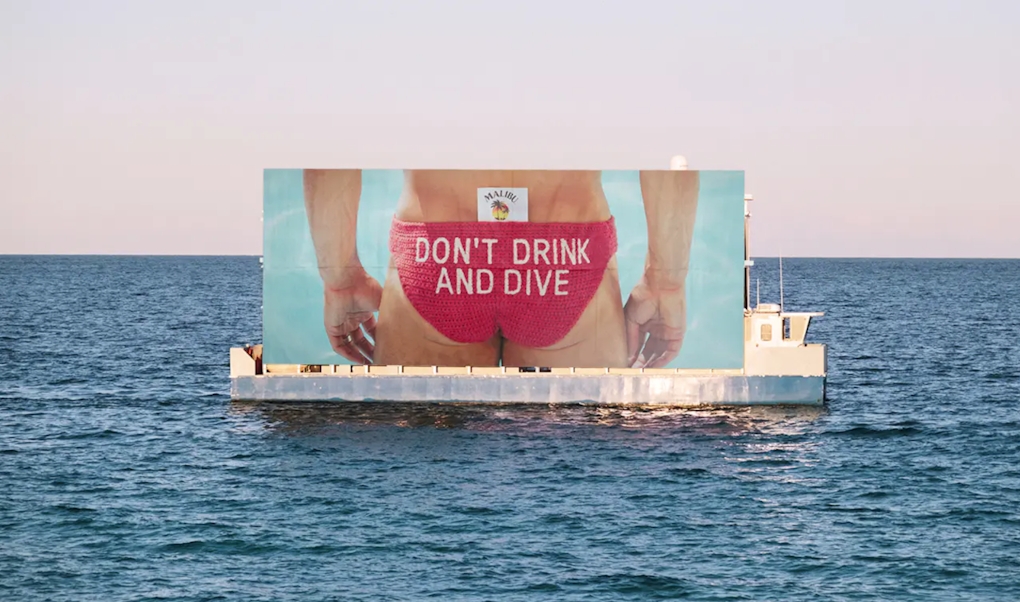 A floating billboard displays Tom Daley's bum in crocheted briefs that display the message 'don't drink and dive'