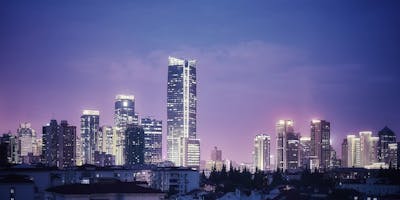 Photograph of Shanghai city at night with skyscrapers lit up against a purple-blue sky