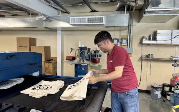 person taking textiles off of a conveyor belt