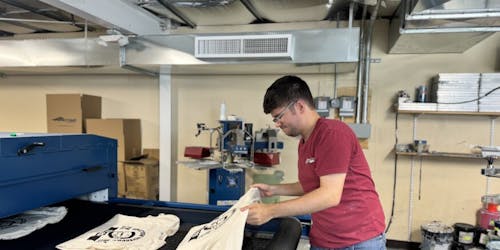 person taking textiles off of a conveyor belt