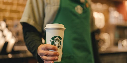 Starbucks barista holding a takeaway coffee