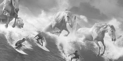 Crashing waves turn into white horses as surfers ride them