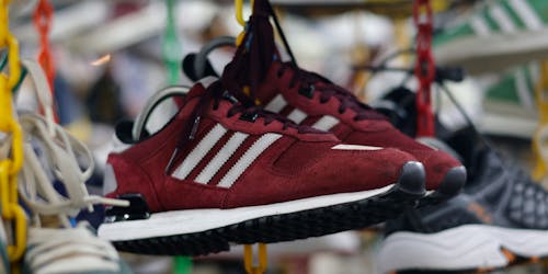 A pair of red Adidas trainers hang from a rail